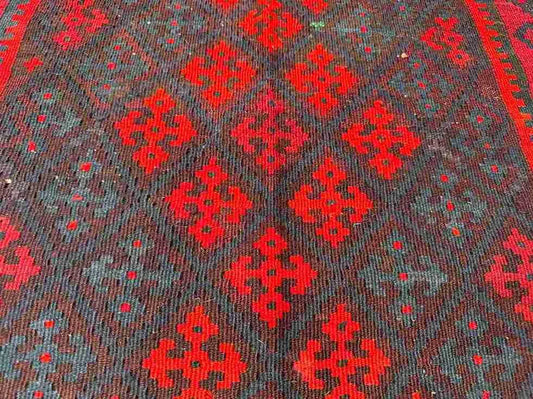 Close-up of wool flatweave – handmade Kilim rug in small size with red and earthy tones.